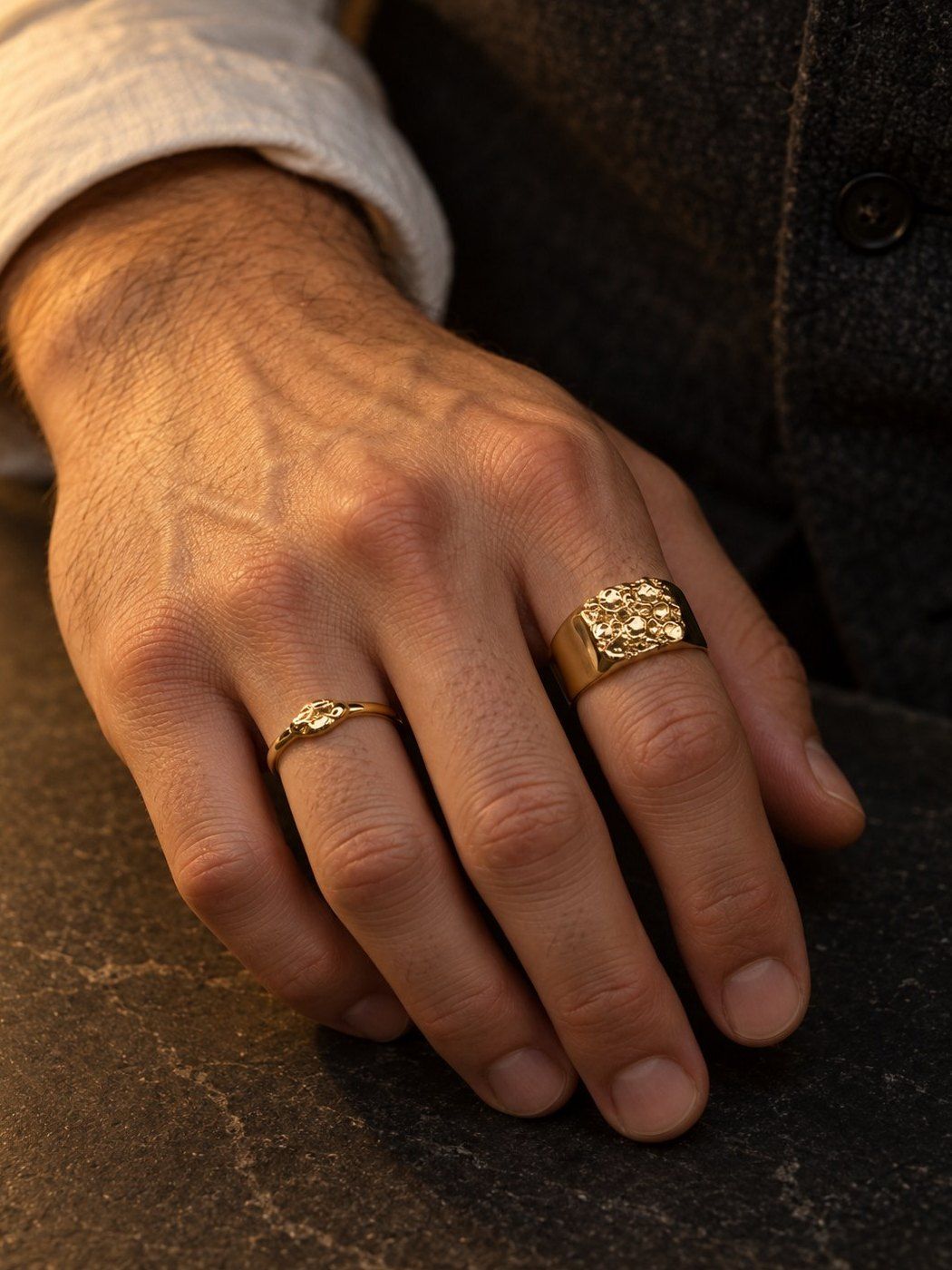Bullion No. 502 and Grain No. 525 in solid 14K gold, together on one hand on a dark slate counter