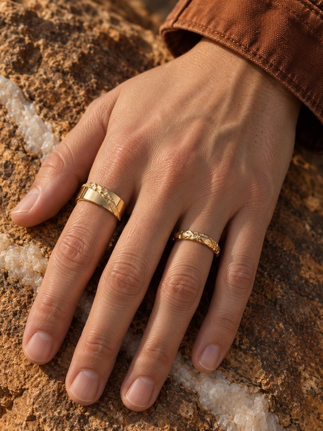 Fault Line No. 518 and Slim No. 024 in solid 14K gold, together on one hand on ochre rock