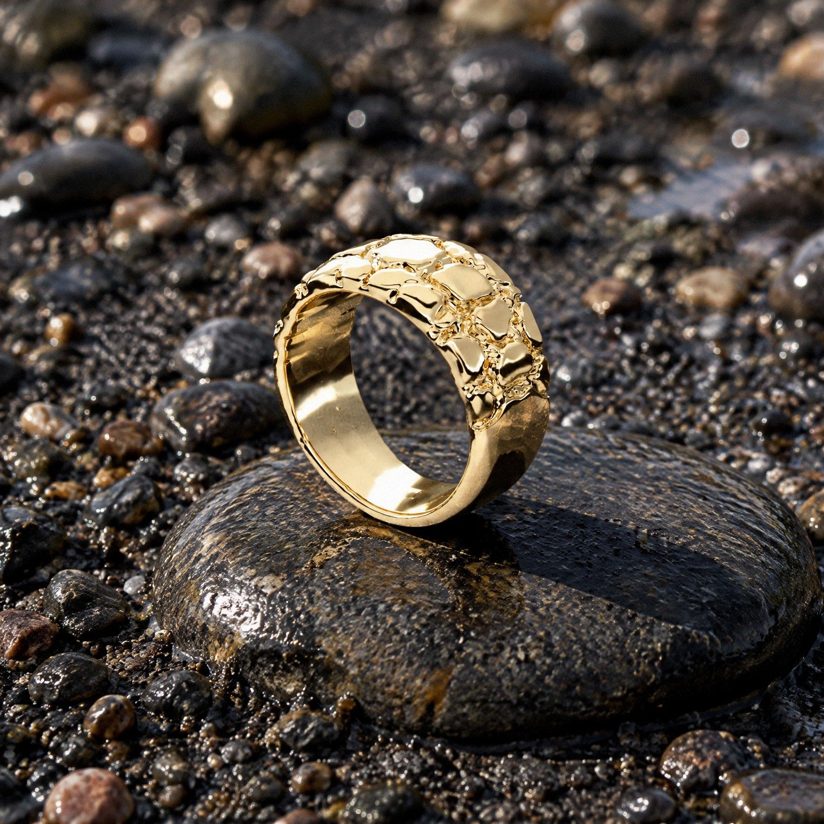 No. 507 Riverbed nugget ring in 14K yellow gold, on a wet dark pebble in black river sand