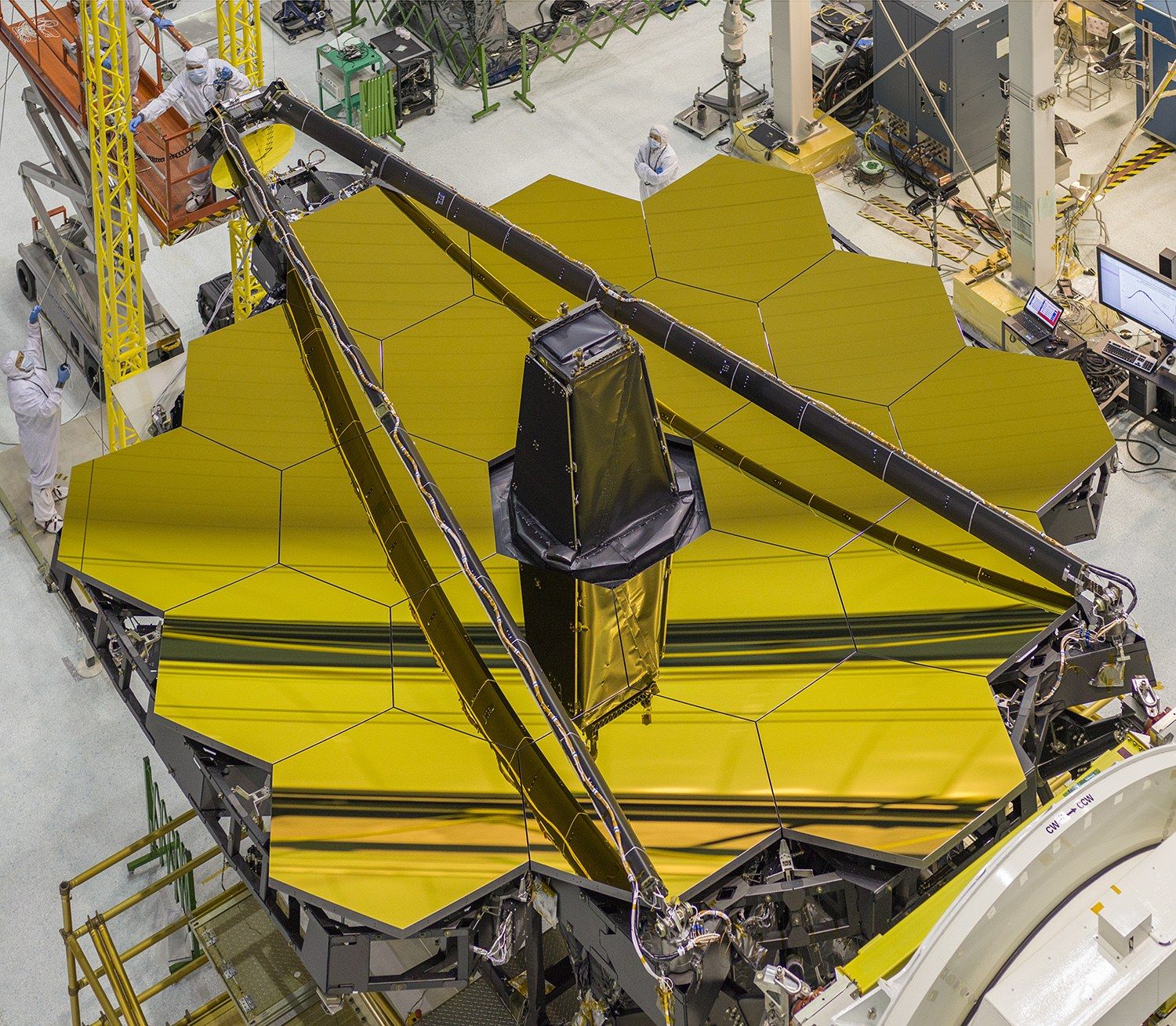 Webb's primary mirror seen from above in a clean room: 18 gold hexagons forming one large mirror, with the folded supports of the secondary mirror lying across it